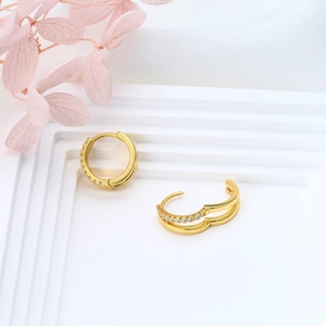 Detail of gold double-hoop silver earrings with white zircon on geometric stand