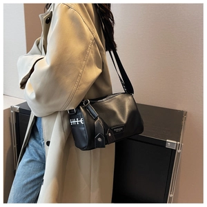Black leather crossbody pillow bag with wide sporty letter strap shown on a model