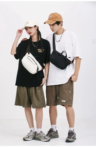 Close-up of minimalist black and white crossbody bags with bright orange side label detail