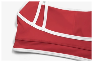 Detail of red sports bra with white contrast piping and dual elastic straps