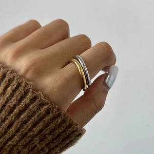 Close-up of gold and silver polished stainless steel rings worn with a brown knit sweater