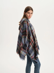 Detail of plaid poncho shawl featuring soft fabric texture and long fringe edges