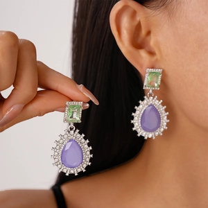Macro view of vintage teardrop earrings with purple crystal and green gemstones