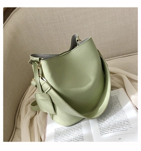 Vue détaillée du sac seau vert clair avec garnitures dorées sur chaise beige