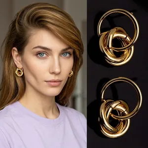 Macro detail of geometric multi-layered interlocking gold hoop earrings in brass finish