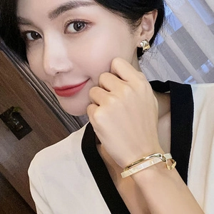 Detail shot of golden geometric earrings and a double-layer bracelet on a model