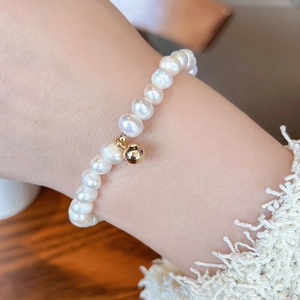 Detailed close-up of natural freshwater pearl bracelet with a small gold-filled round pendant