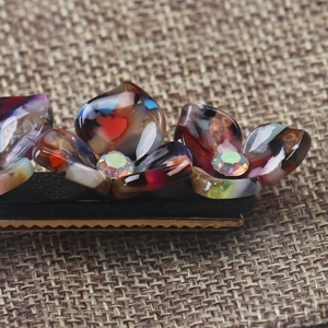 Macro shot of tortoiseshell acetate flower hair clip with sparkling rainbow rhinestone center