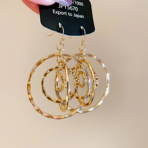 Detailed close-up of golden multi-layered wavy hoop earrings with metal texture