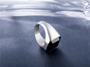 Vue détaillée d'une bague carrée en acier inoxydable argenté sur tissu bleu