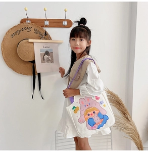 Girl carrying white canvas tote bag with purple straps and cute cartoon illustration