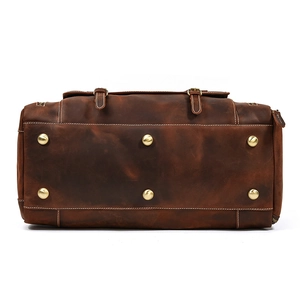 Detail of vintage leather travel bag bottom with protective metal feet and white stitching