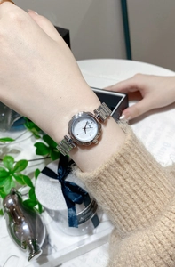 Detailed close-up of a silver floral bezel watch with a pearl dial on a woman's wrist