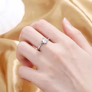 Detailed close-up of a silver six-prong setting solitaire heart ring on golden silk fabric