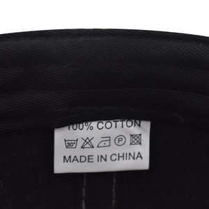 Macro view of 100% cotton washing label with care symbols on black baseball cap