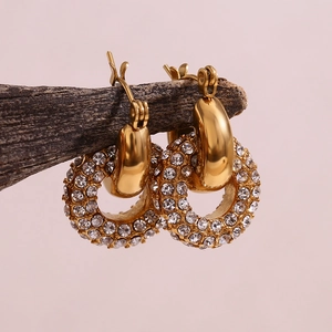 Macro shot of 18K gold plated hoop earrings with micro-inlaid cubic zirconia on wood branch
