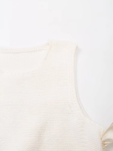 Detail of white knitted vest showing side ribbon bow and premium fine texture
