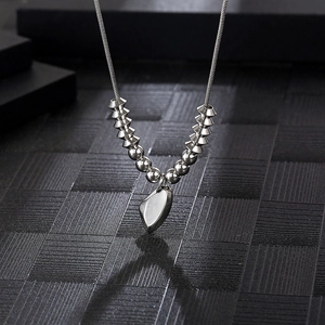 Silver snake chain necklace with V-shaped beads and heart pendant on dark background