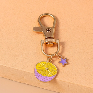 Detailed close-up of golden keychain with lemon slice and purple star charms