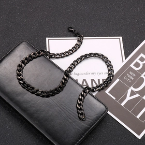 Detail shot of a black stainless steel Cuban chain necklace on a dark leather texture background