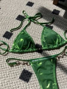 Detail of glossy green metallic bikini fabric with pearl and gold ring accents