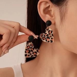 Close-up of leopard print heart resin earrings worn by a model in a retro style