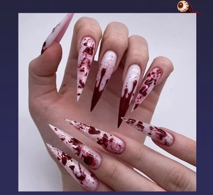 Detailed view of white stiletto fake nails with realistic red blood splatter design