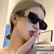 Close-up of black cat-eye sunglasses with gold metal BB logo on the side temple