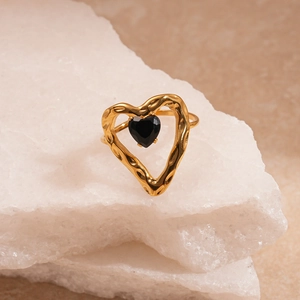 Détail d'une bague coeur en or avec pierre noire sur un support en cristal blanc