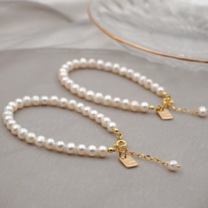 Lustrous white freshwater pearl bracelet with golden Good Luck tag and lobster clasp