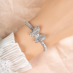 Elegant silver butterfly bracelet with zircon stones worn on wrist against silk background