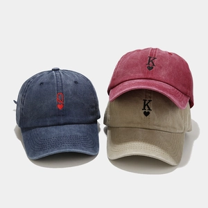 Close-up of vintage washed baseball caps with embroidered poker card Q and K patterns