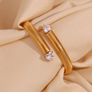 Macro detail of gold-plated snake texture bangle featuring two heart-shaped zircons