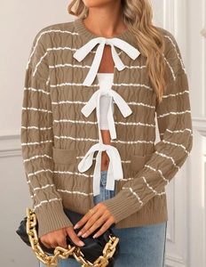 Detail of knitted cardigan with brown stripes and delicate white bow tie closures
