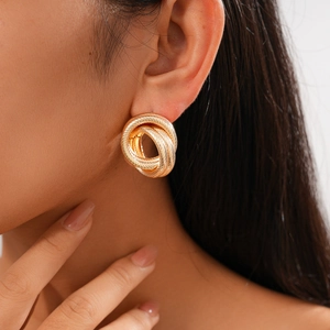 Close-up of a model wearing a gold twisted geometric layered hoop earring set