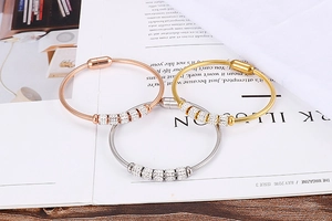 Détail de trois bracelets en acier titane avec finitions or rose, doré et argenté