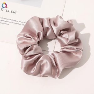 Close-up of silk satin scrunchie in champagne pink featuring elegant fabric texture