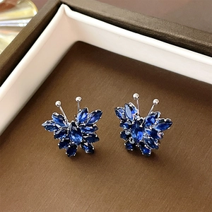 Macro shot of silver butterfly stud earrings with blue zircon stones in a jewelry box