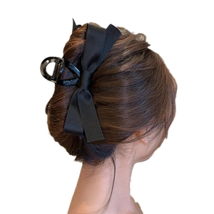 Elegant black velvet bow hair claw clip for women shown on long wavy hair from the back