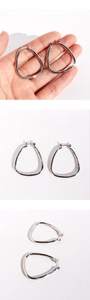 Macro view showing silver irregular triangle geometric hoop earrings on a clean background