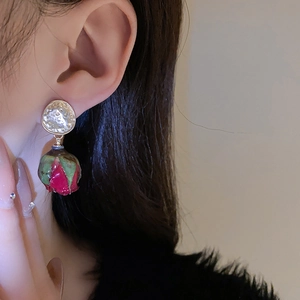 Mannequin portant des boucles d'oreilles vintage avec métal doré et roses séchées rouges