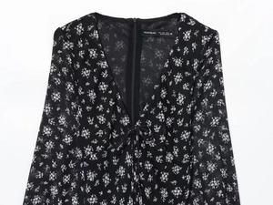 Detail van de V-hals met strikje en bloemenprint op zwarte chiffon jurk
