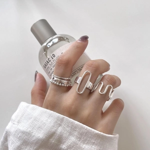 Set of minimalist 925 sterling silver geometric rings on hand holding a perfume bottle
