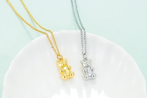 Collane con ciondolo a forma di orsetto 3D in oro e argento su vassoio a conchiglia