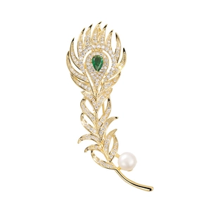 Close-up of peacock feather brooch with gold plating, green zircon and white pearl