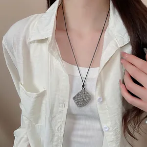 Minimalist silver woven square pendant necklace with black wax rope on model in white shirt