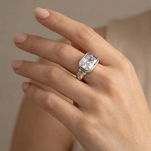 Detail of a twisted silver band ring with a large rectangular clear glass stone on finger