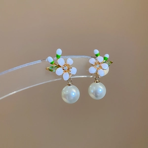 Makroaufnahme der 18k vergoldeten Blumenohrringe mit Perlen und funkelnden Zirkonia