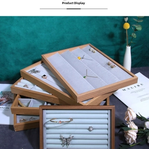 Close-up of tiered wood jewelry trays with gray velvet lining for rings and necklaces