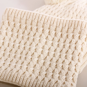 Macro detail of cream cable knit texture and ribbed edge on thick winter scarf